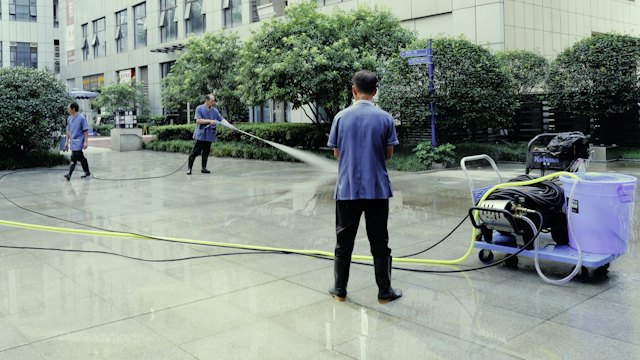 Worker pressure washing a paved plaza