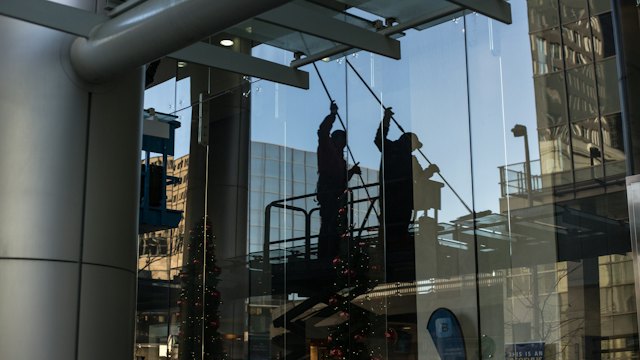Window cleaners washing large glass panes